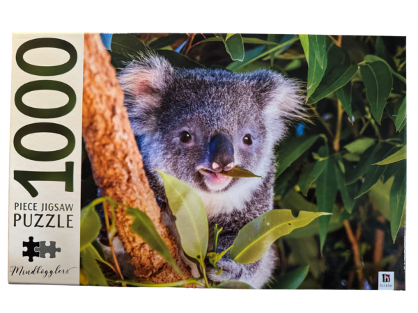 A koala bear is eating leaves off of a tree.